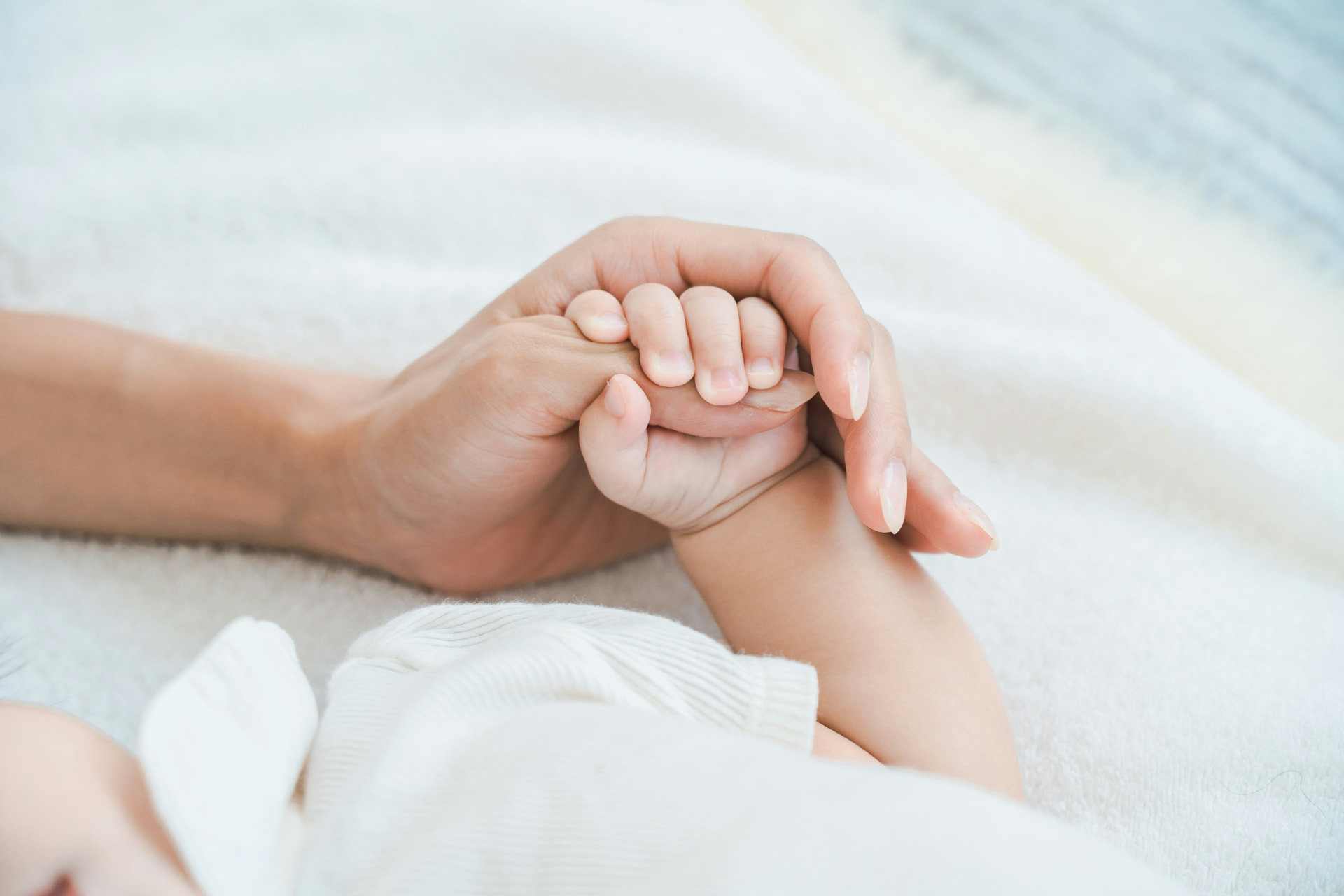 Elternhand hält die Hand eines Neugeborenen